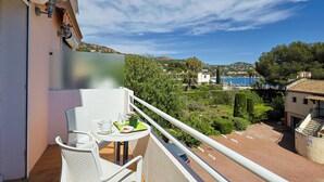 Un balcon avec une table et des chaises, offrant une vue panoramique sur une ville côtière et les collines environnantes.