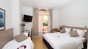 Une chambre d’hôtel avec deux lits, une télévision, un bureau et une fenêtre avec des rideaux.
