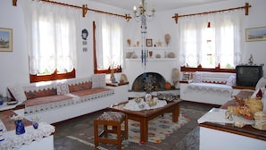 A traditional living room with a sofa set, a fireplace, and a television. - Afroditi (Skopelos)