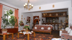 A traditional living room with a sofa, coffee table, and a bar area with shelves of bottles. - Afroditi (Skopelos)