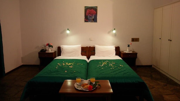 A hotel room with two beds, a green bedspread, a small table with breakfast, and a painting on the wall. - Afroditi (Skopelos)