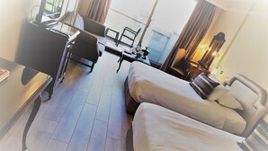 A hotel room with two beds, a desk, a chair, a small table, and a lamp. - Karaca Otel (Izmir)
