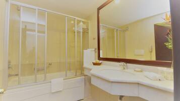 Une salle de bain avec une douche à parois de verre, un lavabo blanc et un grand miroir.