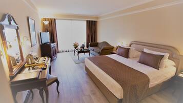 A hotel room with a large bed, a desk with a lamp, a television, and a window with curtains.