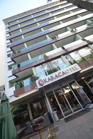 A multi-story hotel with a modern design, featuring balconies, large windows, and a prominent entrance. - Karaca Otel (Izmir)