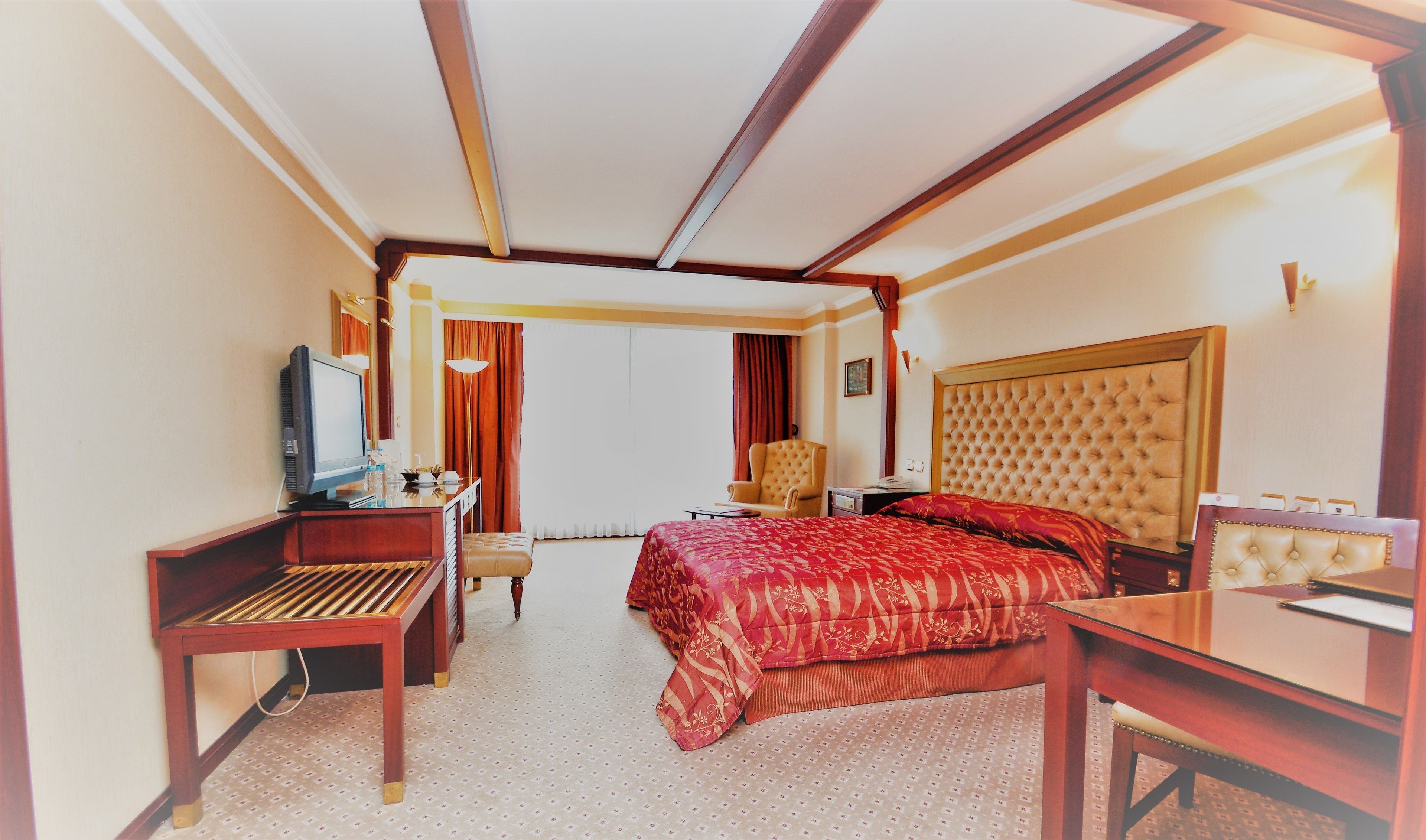 A hotel room with a bed, a desk, a television, and a chair.