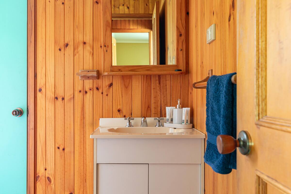 A wooden interior with a white sink, mirror, and towel rack.