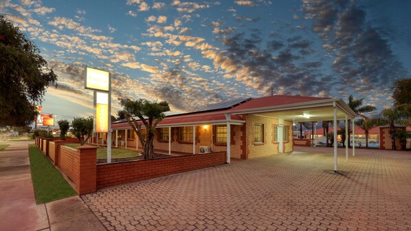 A hotel with a brick facade, a covered outdoor area, and a sign indicating vacancy.