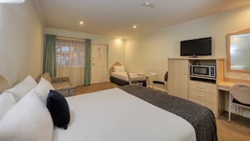 Una habitación de hotel con cama, escritorio, silla, televisor y microondas.