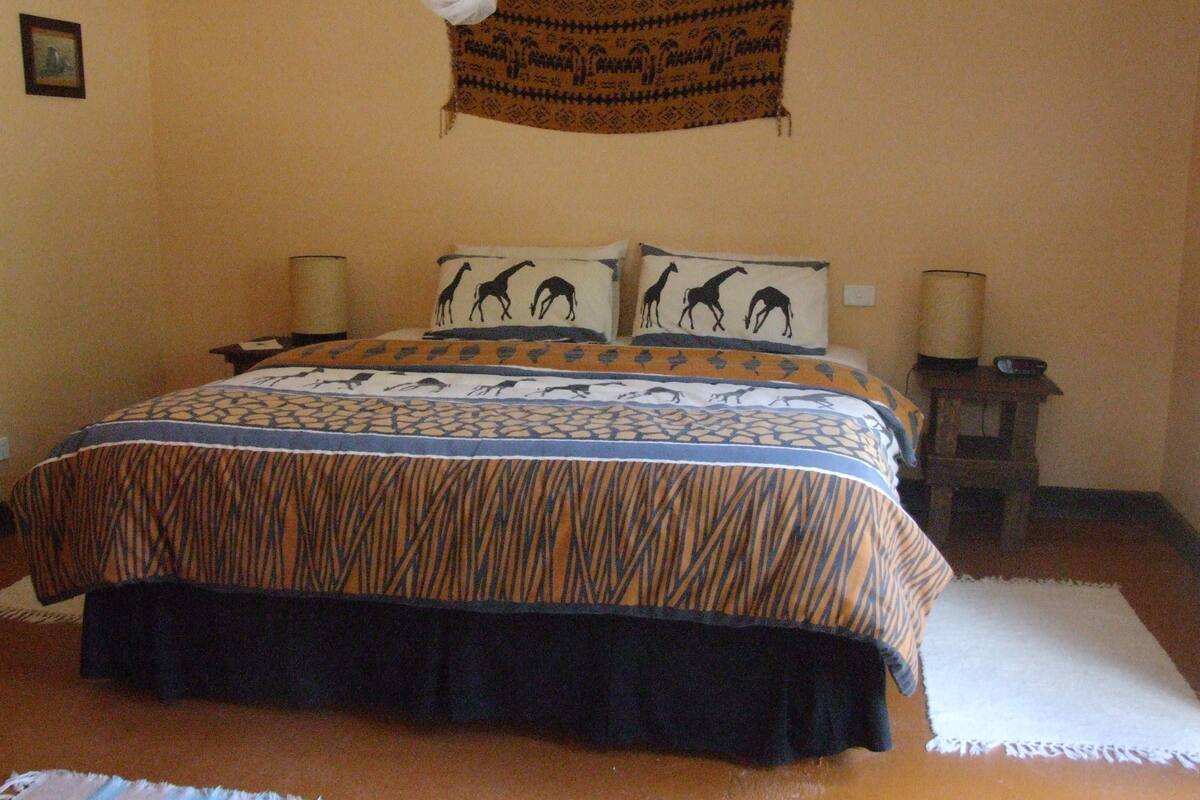Un dormitorio con cama, dos mesitas de noche, un adorno en la pared y una alfombra.
