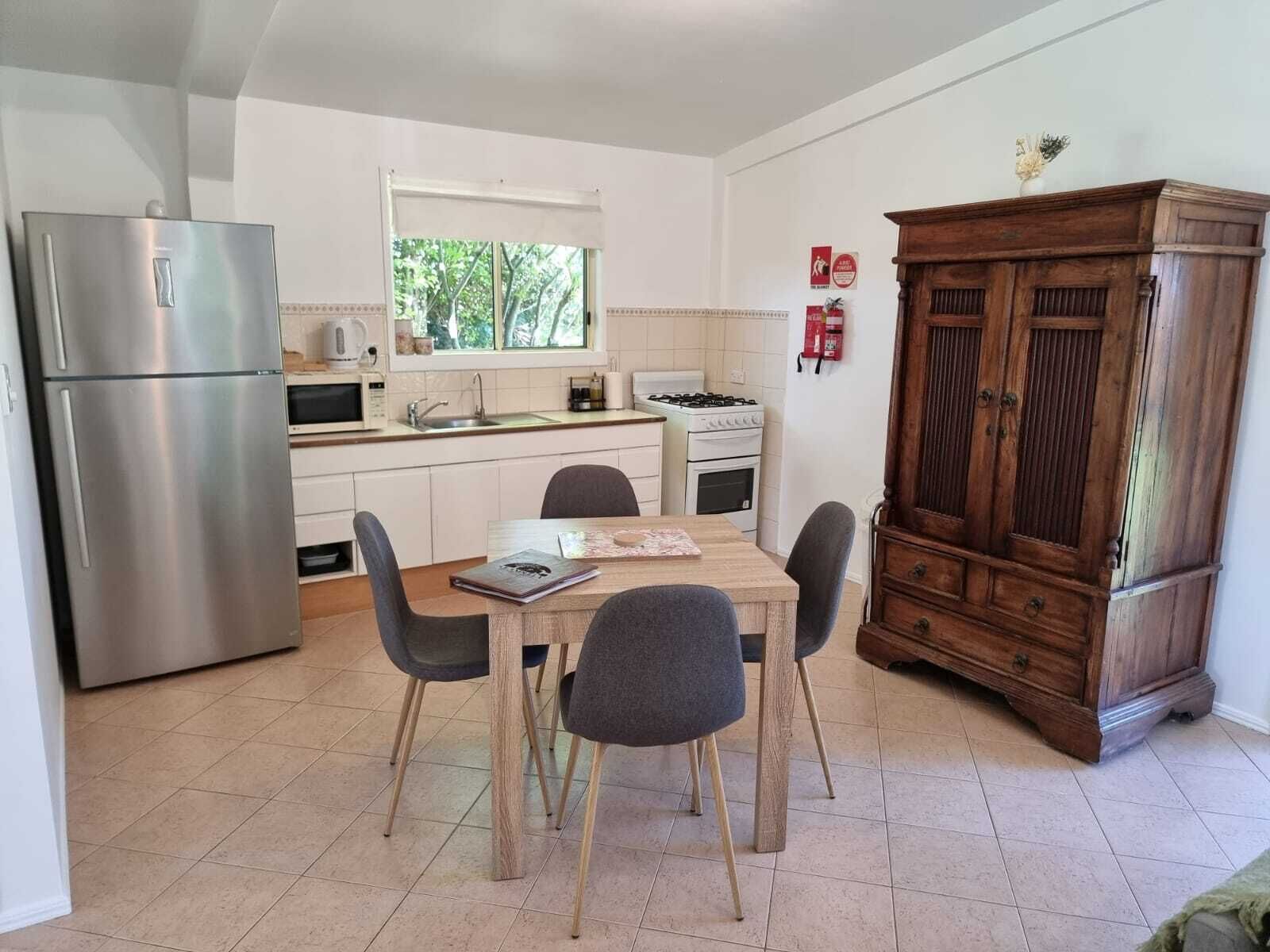 Une cuisine compacte équipée d’un réfrigérateur, d’une cuisinière, d’un four à micro-ondes et d’un meuble en bois.