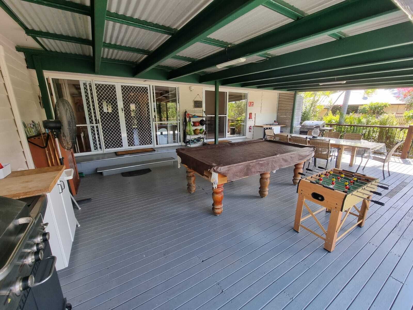 An outdoor patio with a pool table, foosball table, and grill area.