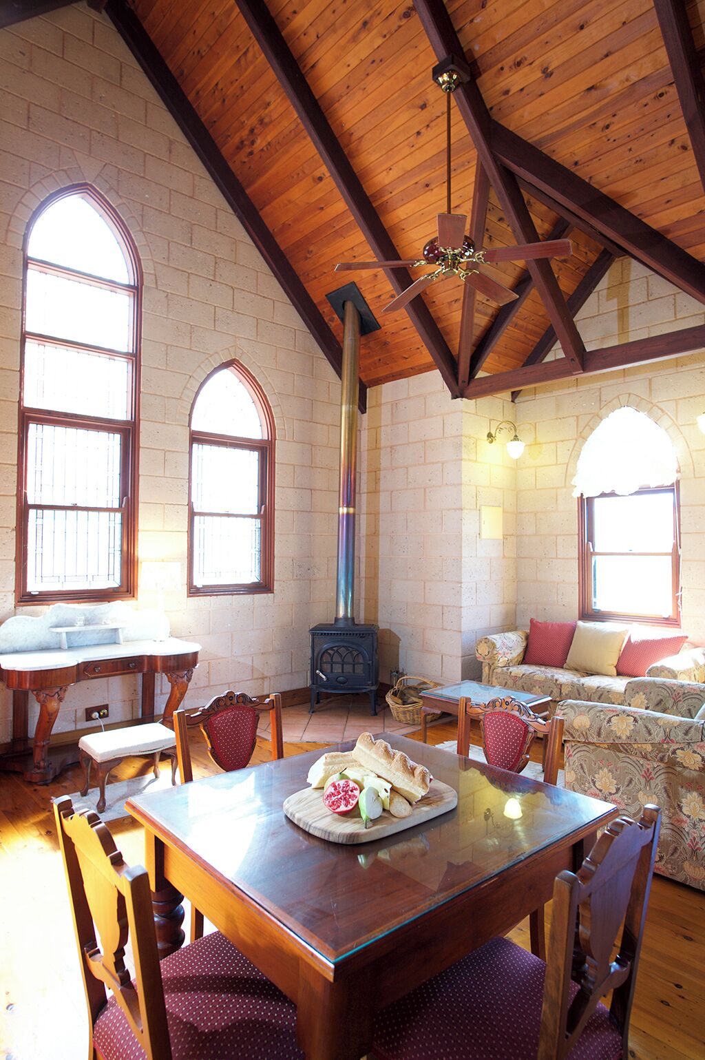 Une pièce chaleureuse avec un plafond en bois, une cheminée en pierre, une table à manger avec des chaises et un canapé.
