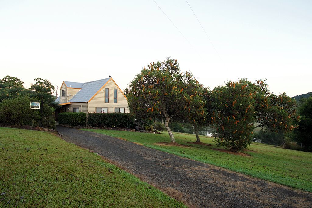 A house with a sloped roof and a paved driveway leading to a grassy area.