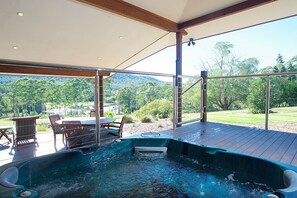 Un jacuzzi en una terraza de madera con vistas a un paisaje exuberante.