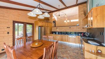 Una cocina amplia con armarios de madera, una gran mesa de comedor e iluminación moderna.