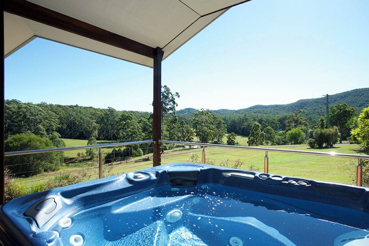 A hot tub with a clear view of a lush green landscape and hills in the background.