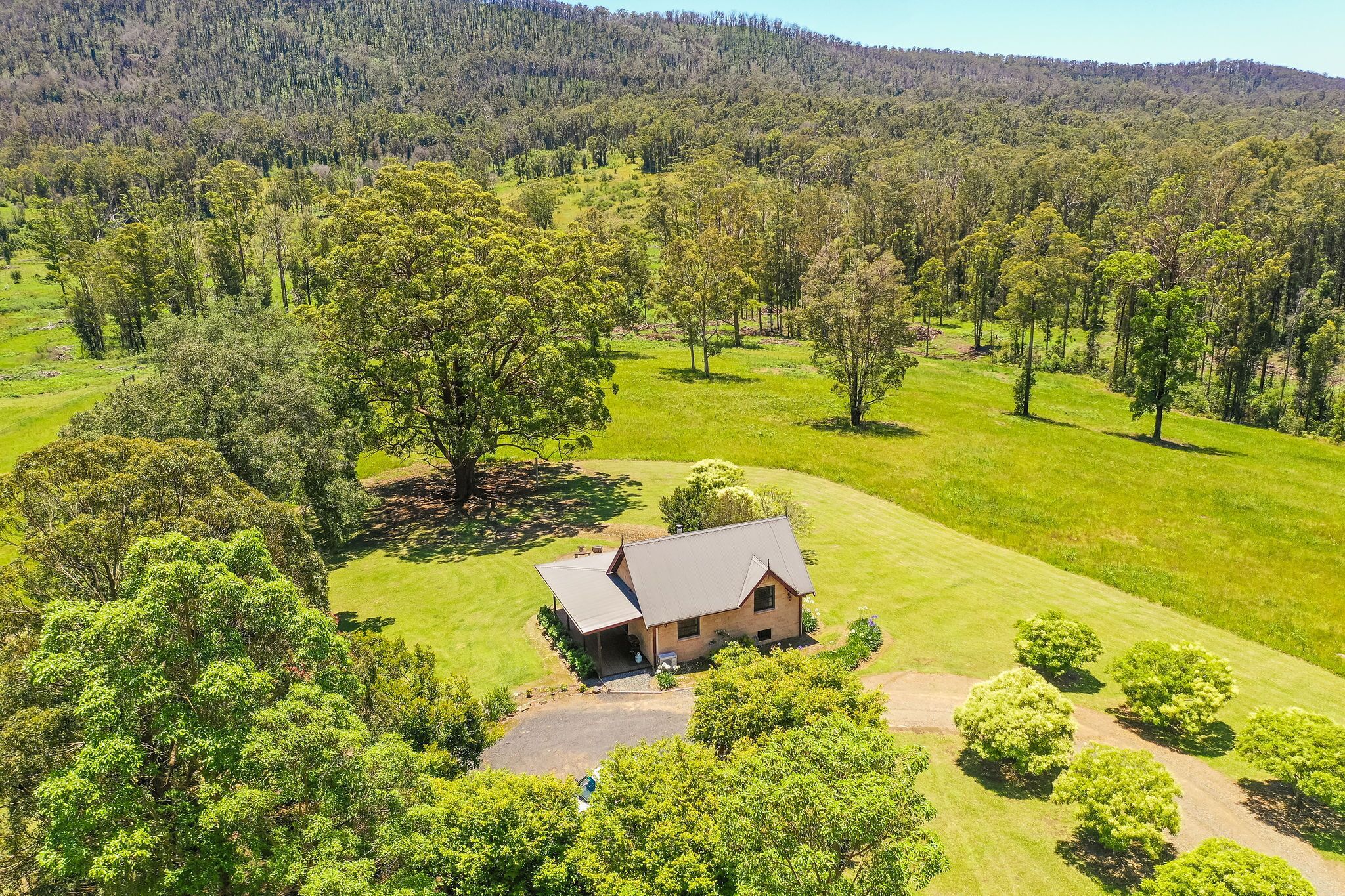 A single-story house with a sloped roof, surrounded by a well-maintained lawn and trees.