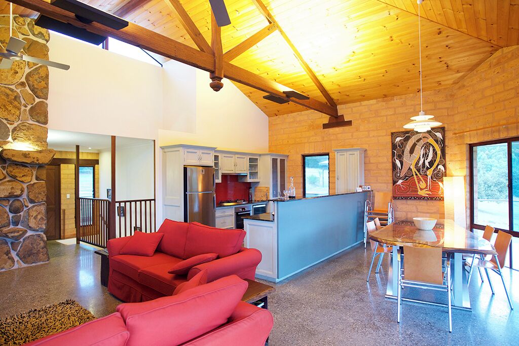 A spacious living area with a red sofa, a dining table, and a kitchen in the background.