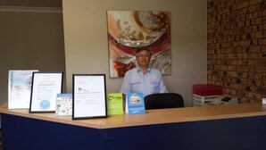 En receptionsdisk med inramade diplom, en tavla och en tegelvägg.