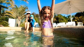 Un área de piscina con agua cristalina, palmeras y sillas de descanso.