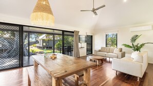 Un amplio espacio de sala con una mesa de madera, un sofá y un ventilador de techo.