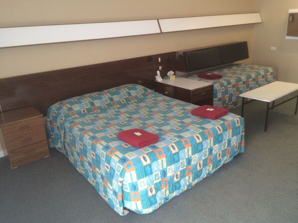 A hotel room with two beds, a desk, a chair, and a small table. - City Beach Motel (Wollongong)