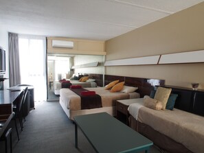 A hotel room with two beds, a desk, a chair, and a bench. - City Beach Motel (Wollongong)