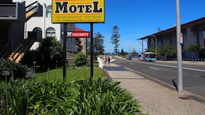 A City Beach Motel sign with amenities like serviced apartments, video movies, air conditioning, spa suites, and B&B options. - City Beach Motel (Wollongong)
