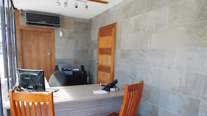 A small office with a desk, two chairs, a printer, and a television on the wall. - City Beach Motel (Wollongong)