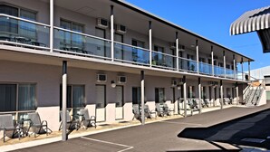 A multi-story motel with outdoor seating and a staircase leading to the upper level. - New England Motor Inn (Armidale)