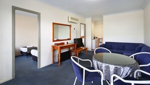 A hotel room with a dining area, a sofa, a TV, and a desk.