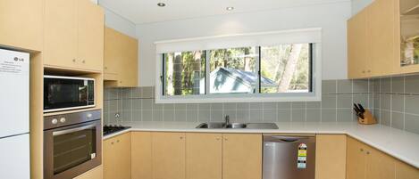 Una cocina moderna con electrodomésticos integrados, un ventanal y vistas al exterior.