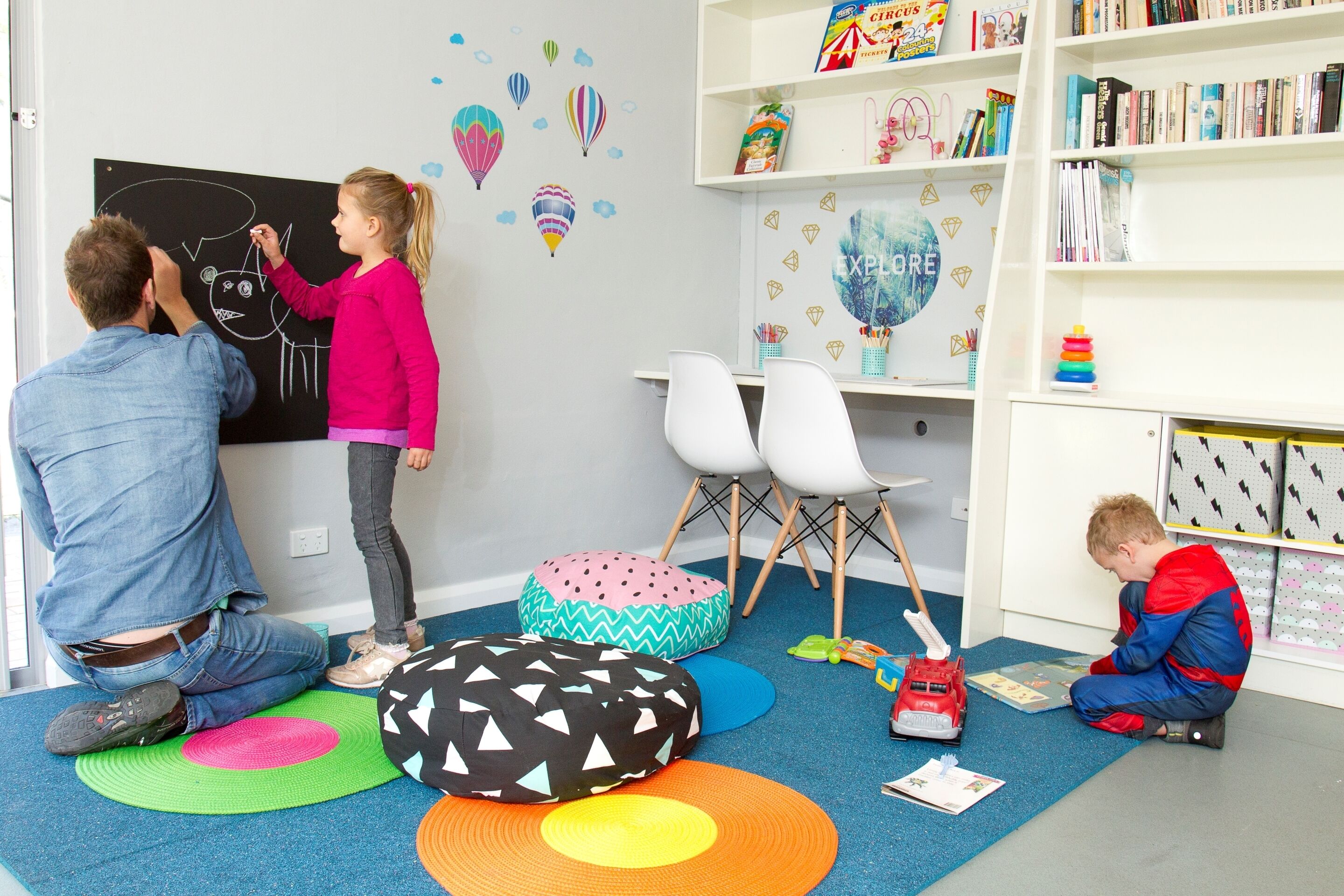 A room with a blackboard, colorful bean bags, a bookshelf, and a toy car.