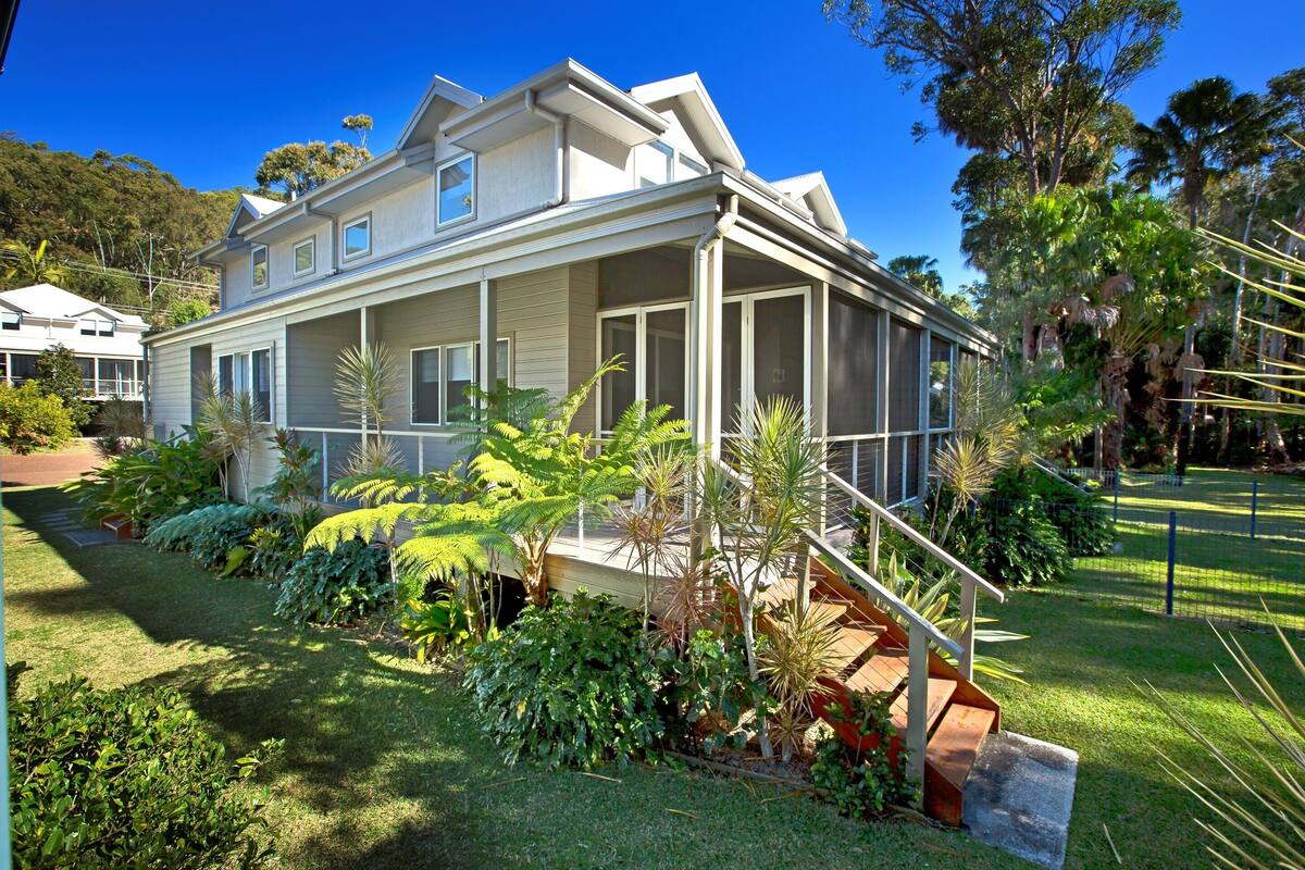 A two-story house with a covered porch and a staircase leading to the upper floor.
