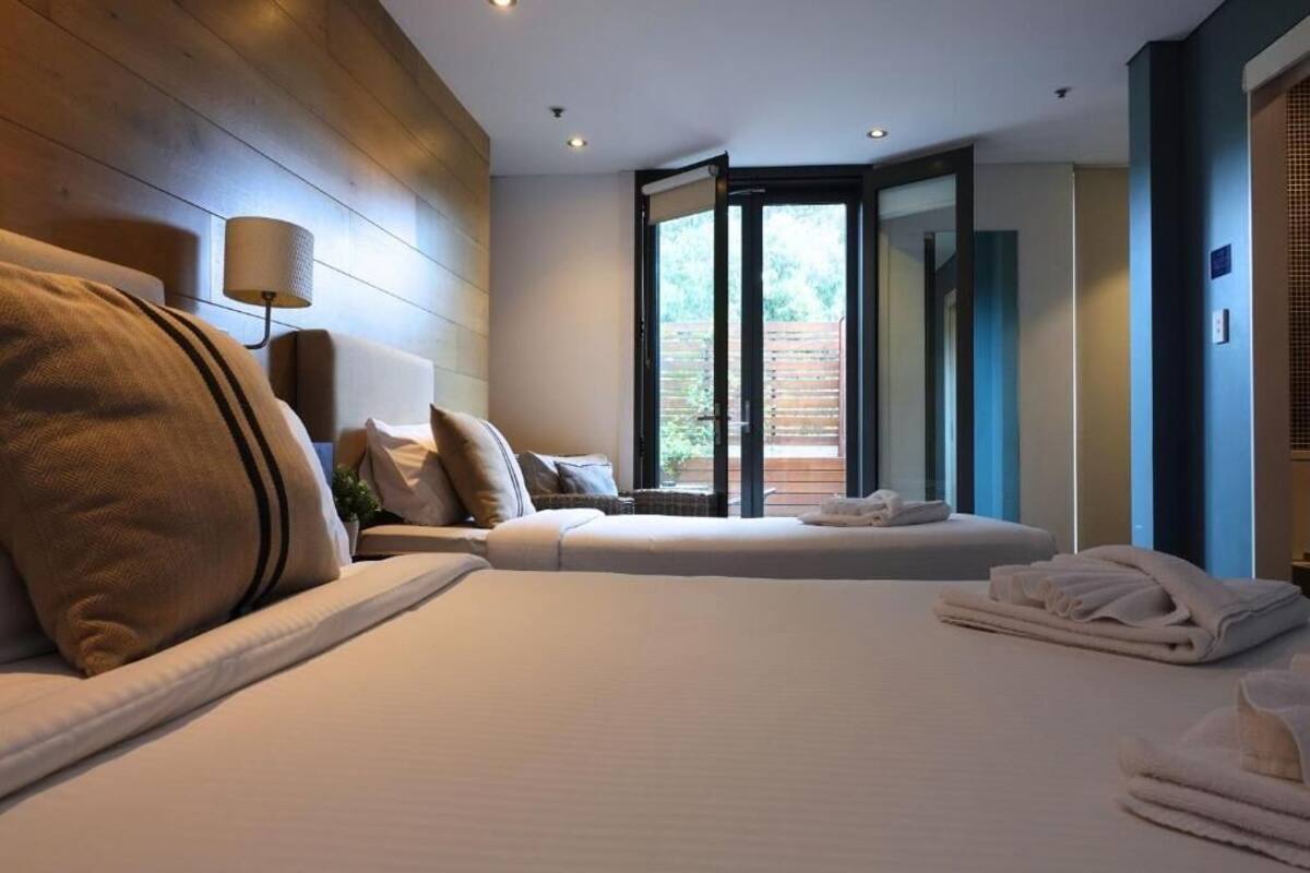 Une chambre d’hôtel moderne dotée d’un grand lit, d’un lit plus petit et d’un coin salon offrant une vue sur l’extérieur.