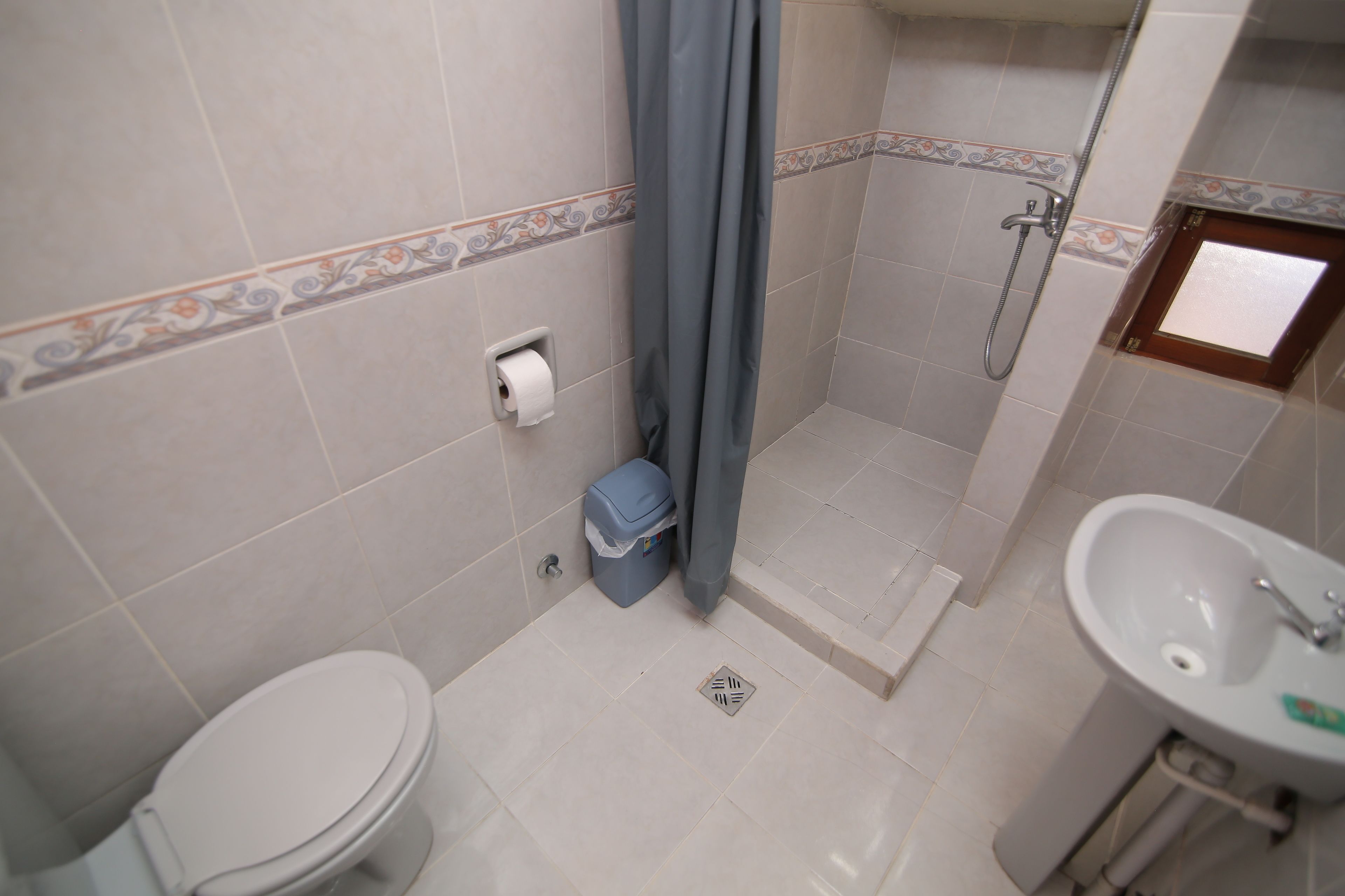 A bathroom with a toilet, shower, and sink.