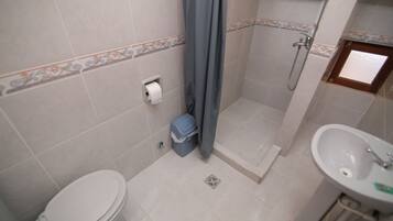 A bathroom with a toilet, shower, and sink.