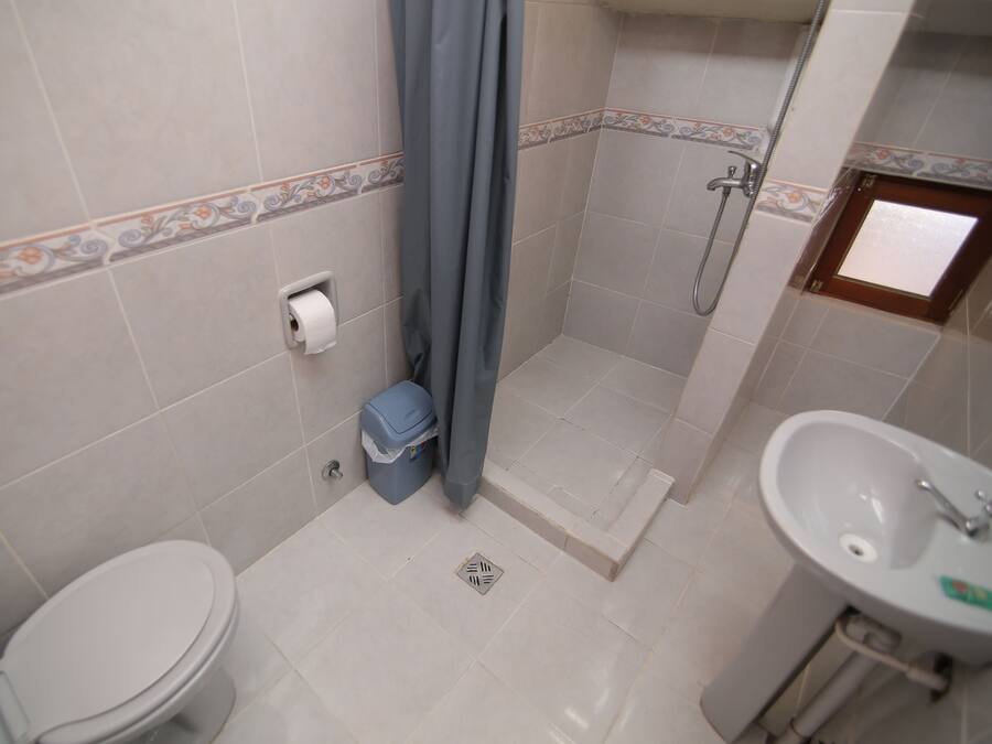 A bathroom with a toilet, shower, and sink.