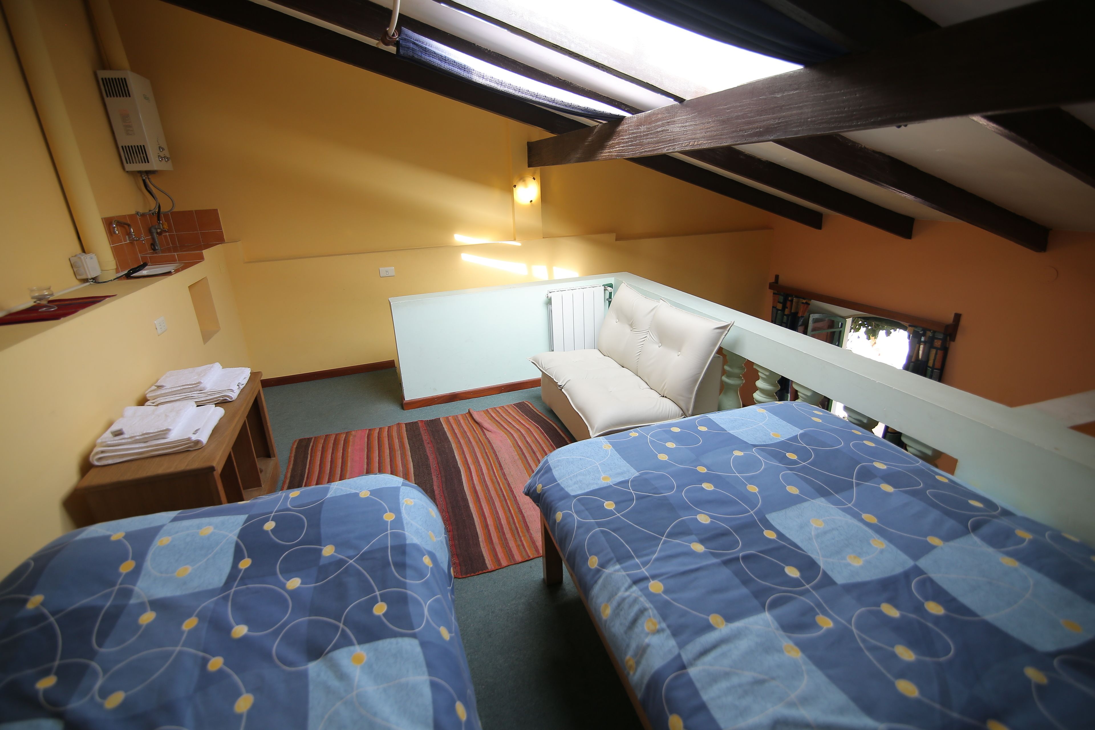 Een kamer met twee bedden, een kleine kitchenette, een raam met uitzicht en een plafondventilator.