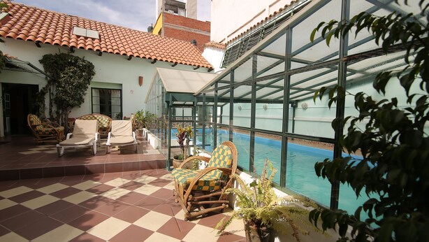 Un espacio al aire libre cubierto con piso a cuadros, sillones de descanso y vista a una piscina.