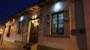 Un edificio con fachada de madera, una escalera y una ventana con barrotes.