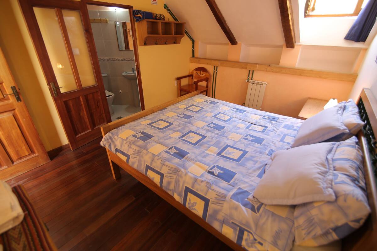 A bedroom with a wooden bed, a chair, a wooden shelf, and a window.