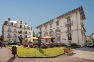 Un edificio con mesas al aire libre y una estatua en el centro.