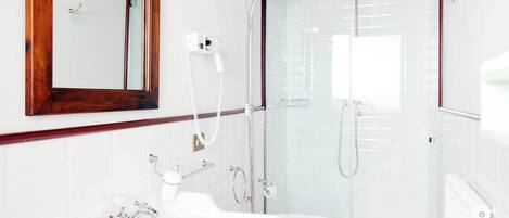 A modern bathroom with a glass shower enclosure, a white sink, and a wooden-framed mirror.