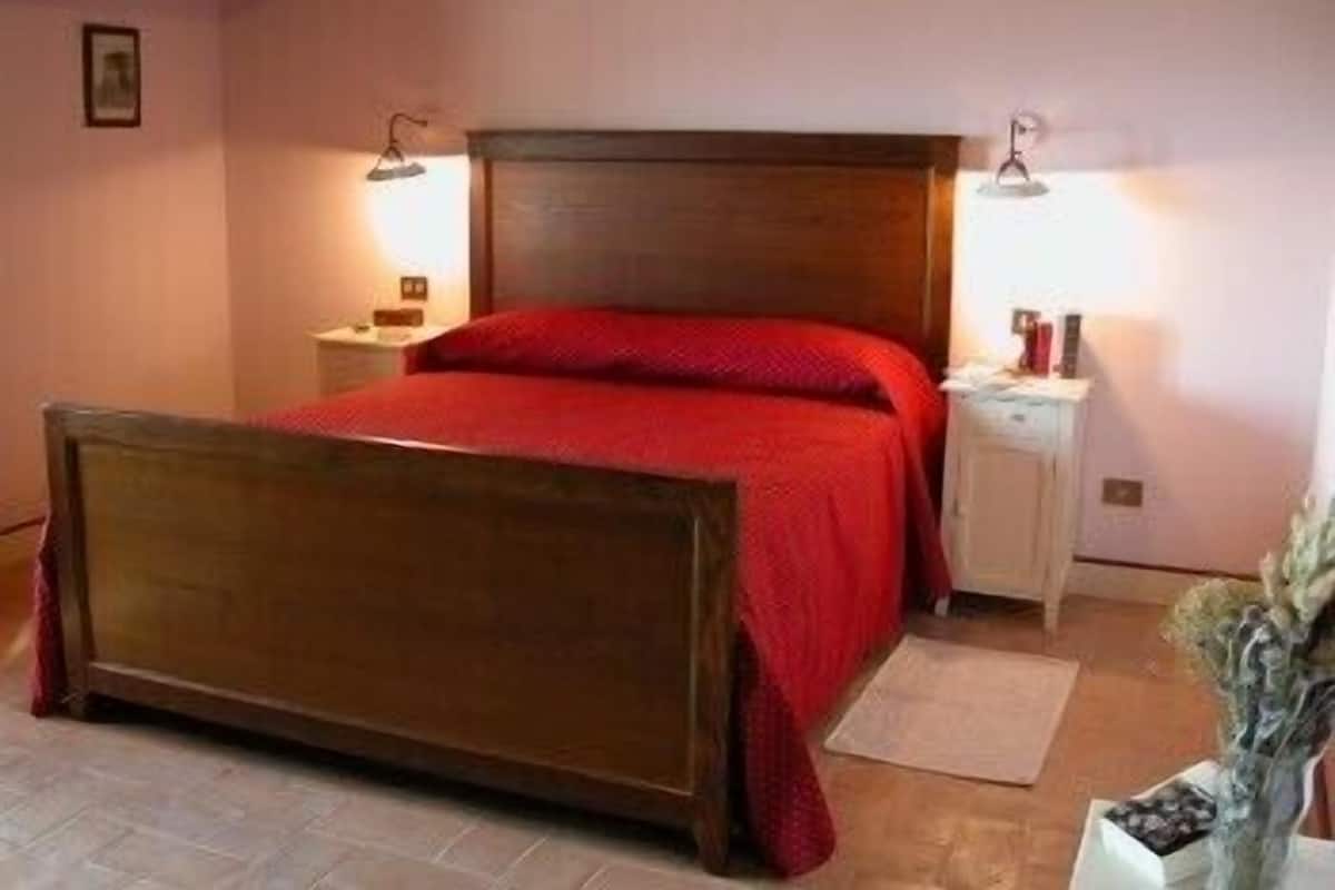 Un dormitorio con una cama de madera, una mesita de noche, una lámpara y una pequeña mesa.