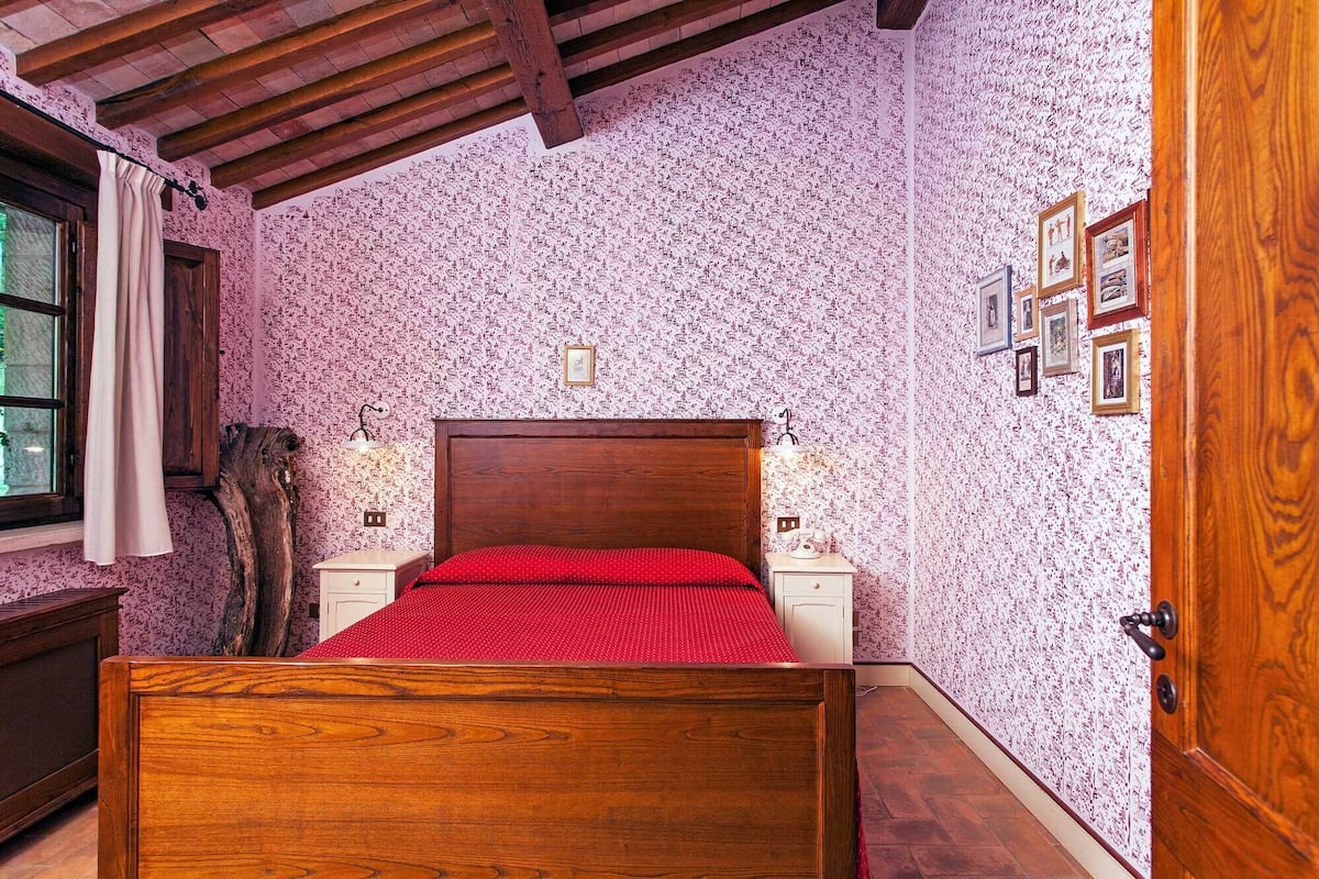 Un dormitorio con una cama de madera, dos mesitas de noche, un armario de madera y una puerta.