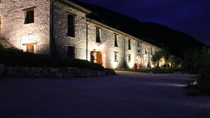 A stone building with a gravel driveway and a stone wall.