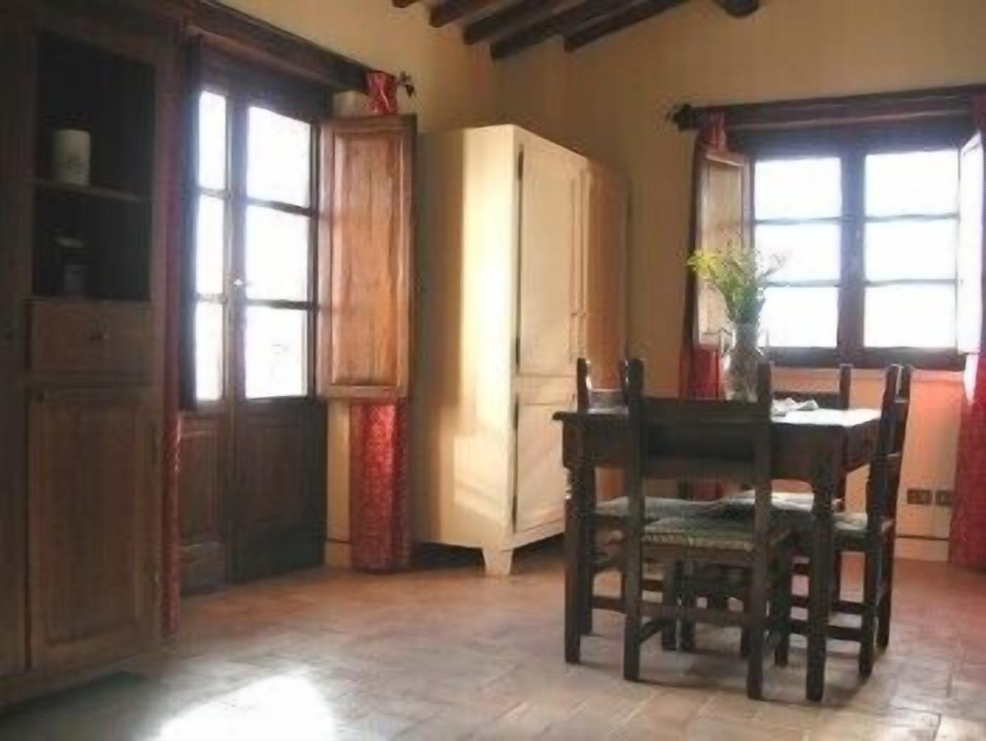 A dining area with a wooden table and chairs, a cabinet, and a window with curtains.