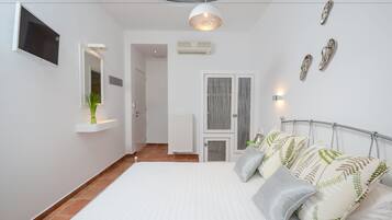 Un dormitorio moderno con una cama grande, un televisor en la pared y una lámpara de techo.